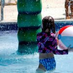 a little girl playing with a beach ball in a pool