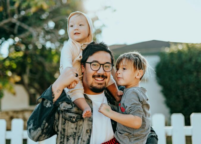 man in white shirt carrying girl in gray shirt