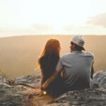man and woman sitting on rock during daytime